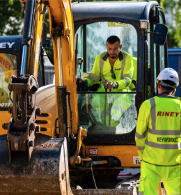 A construction operative in high visibility clothing working in a digger.